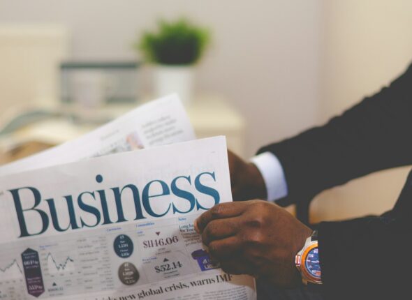 person wearing suit reading business newspaper