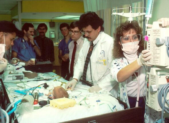 people beside baby lying on bed with medical apparatuses
